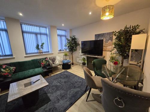 a living room with a green couch and a tv at Cosy family apartment in Bradford