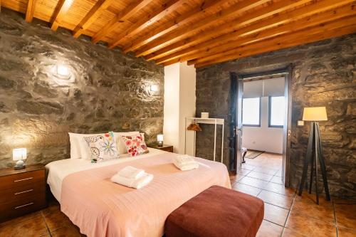 a bedroom with a large bed in a stone wall at Casa Miradouro do Pesqueiro in Feteira Grande