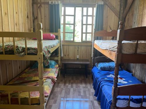 a room with two bunk beds and a window at Galpão, Pousada Paraíso do Arruda in Lages