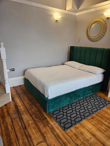 a bedroom with a bed with a green headboard and a mirror at City Centre Location on Corn Street studio in Bristol