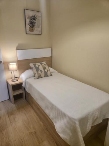a small bedroom with a bed and a lamp at Casa Anita in Luarca