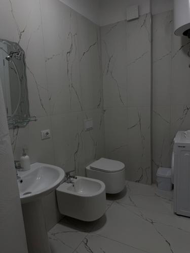a white bathroom with a sink and a toilet at Golden Apartment 1 in Kamëz
