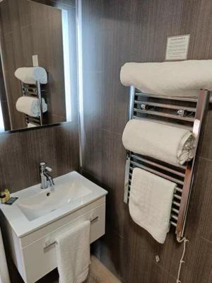 a bathroom with a sink and a mirror and towels at Ye Olde Crown in Edenbridge