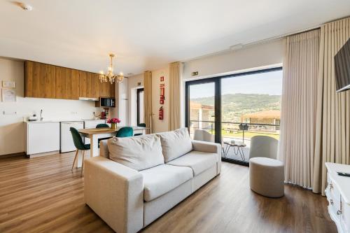 a living room with a white couch and a kitchen at Vale da Fonte - Charming Houses in Ponte da Barca