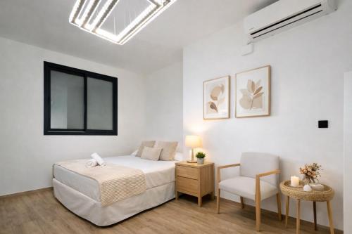 a white bedroom with a bed and a chair at Bigbass Valencia Centro in Valencia