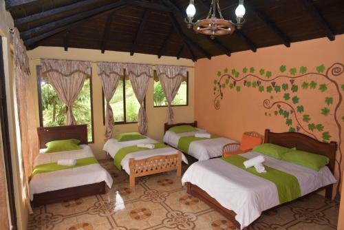 four beds in a room with green and white at Las Orquídeas Runtun Lodge in Baños