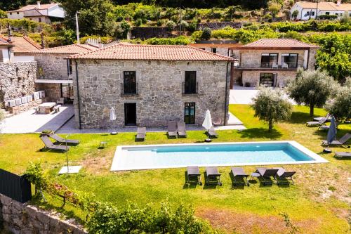 an external view of a stone house with a swimming pool at Vale da Fonte - Charming Houses in Ponte da Barca