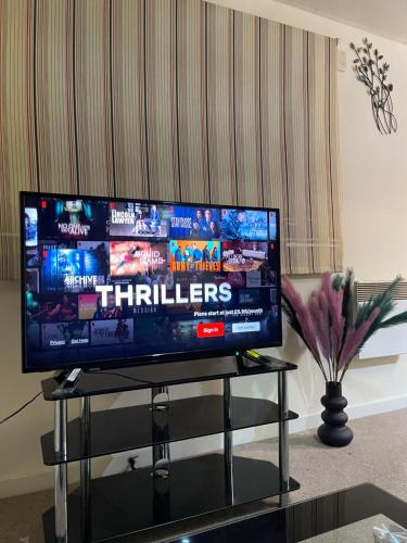 a flat screen tv sitting on a stand in a living room at Casa Centro two bedroom apartment in Wolverhampton
