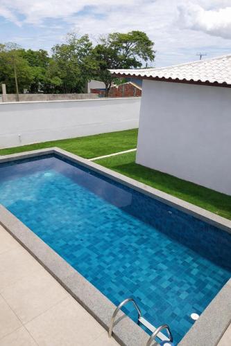 a swimming pool with blue water in front of a house at QUINTAL DE BÚZIOS- casa com piscina e 3 suítes completas in Búzios