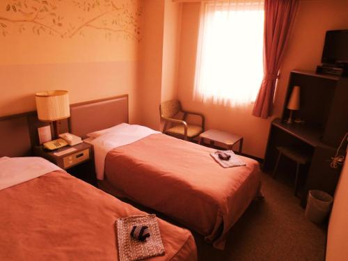 函館市にあるホテルハートインのベッド2台と窓が備わるホテルルームです。