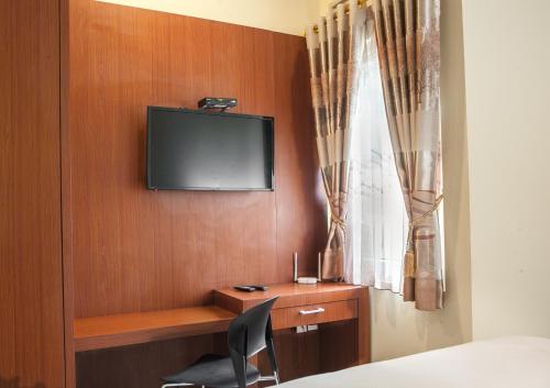 a room with a desk and a tv on a wall at RedDoorz near Trans Studio Mall 2 in Bandung