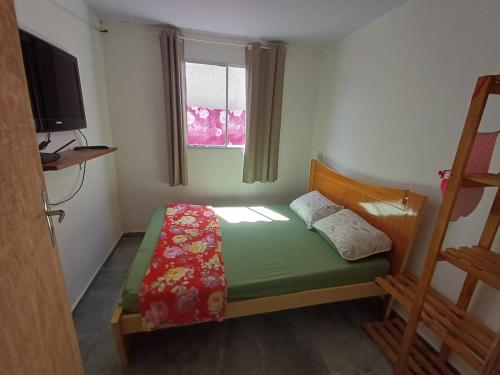 a small bedroom with a bed and a window at Casa simples a 375 mts da praia in Matinhos