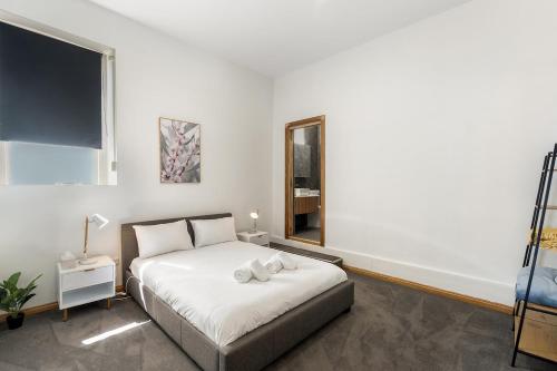 a white bedroom with a bed and a mirror at Modern refine home in Bellerive