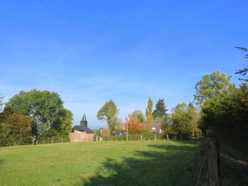 a field with a church and a fence and trees at Le Chant Des Fees in Notre-Dame-de-Courson