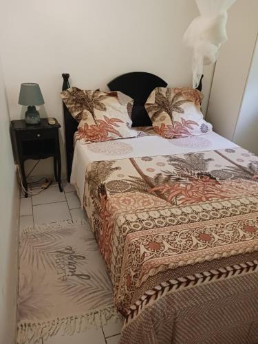 a bed with a comforter and pillows on it at Les Tourterelles in Sainte-Luce
