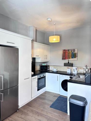 a kitchen with white cabinets and a stainless steel refrigerator at Hostel & home Marlborough street in Dublin