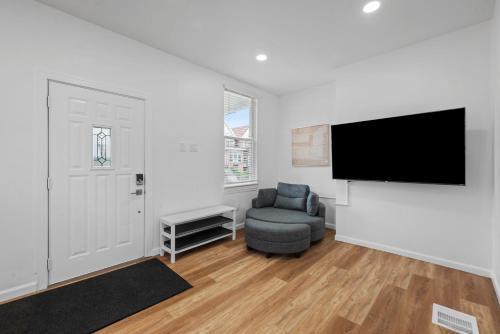 a living room with a tv and a chair at Pittsburgh Spacious and Modern Three Bedroom Apartment with Free Parking in Pittsburgh