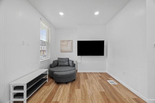 a living room with a chair and a flat screen tv at Pittsburgh Spacious and Modern Three Bedroom Apartment with Free Parking in Pittsburgh
