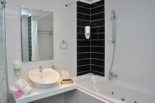 a white bathroom with a sink and a bath tub at Zorbas Beach Hotel in Tigaki