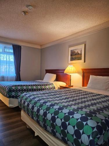 a hotel room with two beds and a window at Moosomin Country Squire Inn in Moosomin