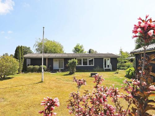 a house with a yard with pink flowers at 6 person holiday home in Faxe Ladeplads in Fakse Ladeplads