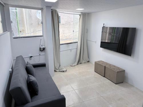 a living room with a black couch and a flat screen tv at The Brooklyn One in Salvador