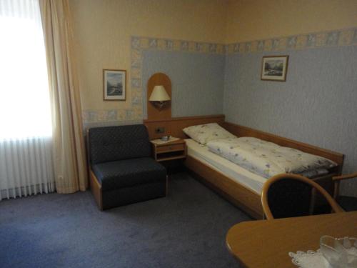 a small bedroom with a bed and a chair at Haus Volkesbach in Liesen