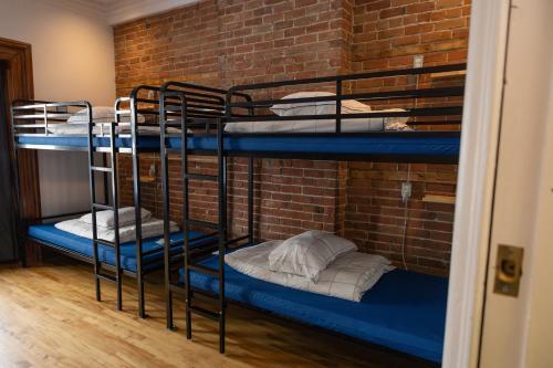 two bunk beds in a room with a brick wall at Auberge Le Treehouse in Montréal