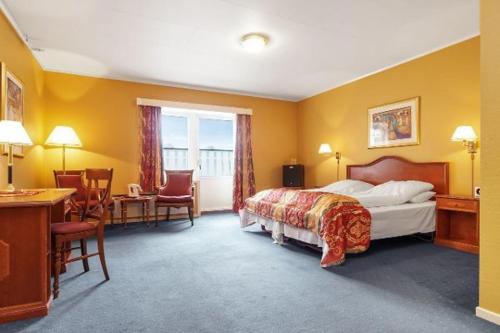 a hotel room with a bed and a desk and chairs at Heia Hotell in Våler i Solør