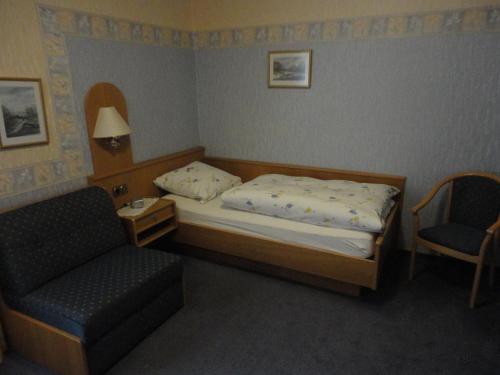 a small bedroom with a bed and a chair at Haus Volkesbach in Liesen