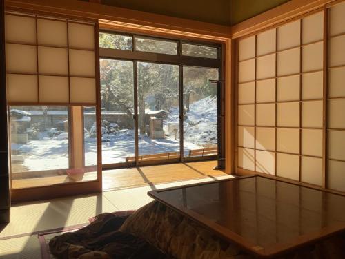 a room with a table in a room with windows at Tsumugu dom in Ueda