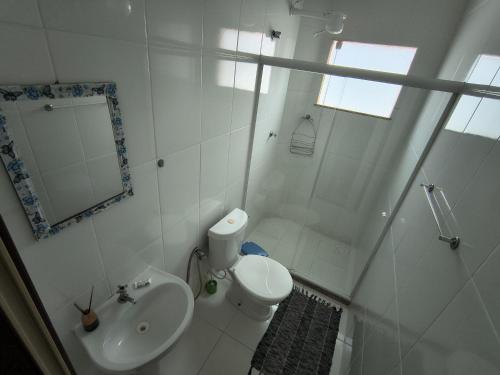 a white bathroom with a toilet and a sink at Casa e Mar Apto aconchegante perto da praia com estacionamento in São Pedro da Aldeia