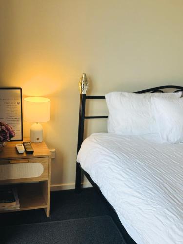 a bedroom with a bed and a table with a lamp at Logies Lodge in Ruakaka