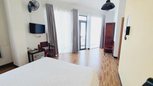 a bedroom with a white bed and a wooden floor at Khách sạn Minh Quang in Phan Rang–Tháp Chàm