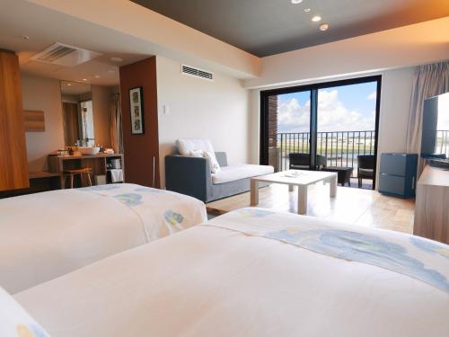 a hotel room with two beds and a balcony at Senagajima Island Resort & Spa in Tomigusuku