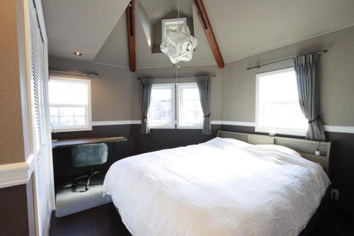 a bedroom with a bed and a desk and windows at KOGUMA AKIRUNO villa in Akiruno