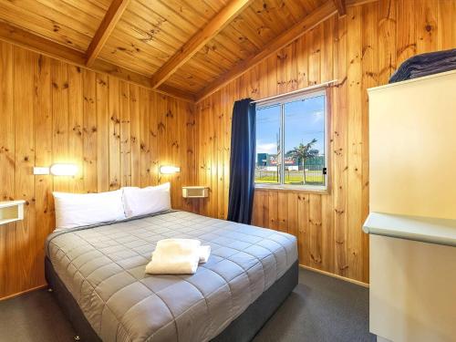 a bedroom with a bed in a wooden room at Heatherbrae Holiday Village in Heatherbrae