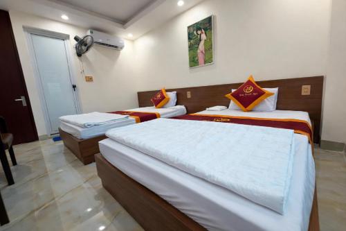 a bedroom with two beds and a door with a fan at SanTran Hotel and Spa in Hai Phong