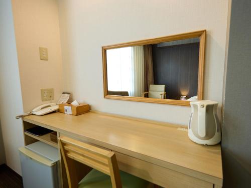 a room with a mirror and a desk with a phone at Nikko Station Hotel Classic in Nikko