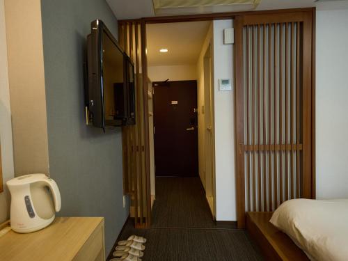 a room with a bed and a door with a television at Nikko Station Hotel Classic in Nikko