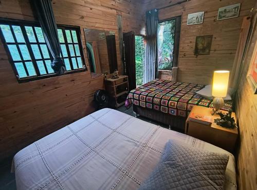 a bedroom with two beds in a wooden cabin at CHÁCARA dos CHEIROS in Atibaia