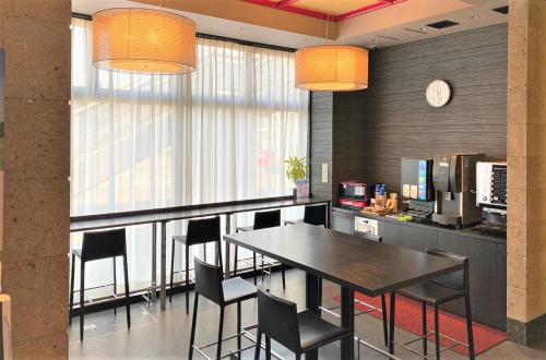 a dining room with a table and chairs and a clock at SAKURA SKY HOTEL KASHIWA(桜スカイホテル柏) in Kashiwa