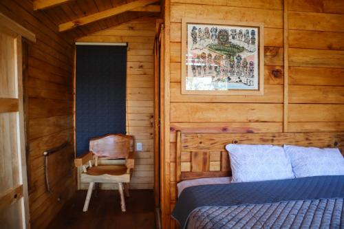 a bedroom with a bed and a chair in a cabin at Casas Calenda in San Mateo Río Hondo