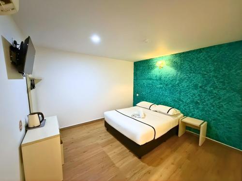 a bedroom with a bed and a green wall at Seeds Hotel Cheras Maluri in Kuala Lumpur