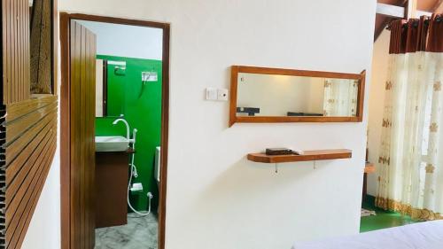 two pictures of a bathroom with a mirror and a sink at Bliss Cottage in Gampola