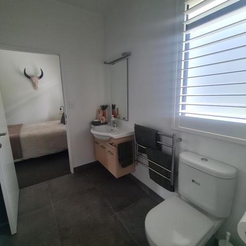 a white bathroom with a toilet and a sink at Sandspit Hideaway in Sandspit