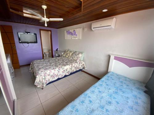 a small room with two beds and a tv at Cobertura luxuosa Marambaia in Barra de Guaratiba