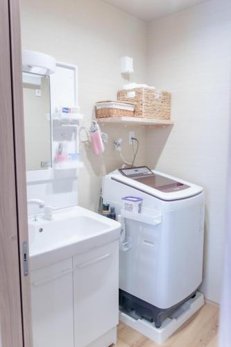 a white bathroom with a sink and a white refrigerator at 三十三 和華waka in Kyoto