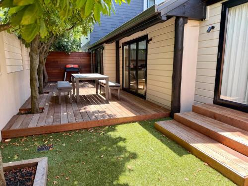 a wooden deck with a table and bench next to a house at Pet friendly downtown Mt Maunganui 3 bedroom home in Mount Maunganui