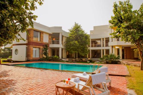 a villa with a swimming pool in front of a house at The Chitvan Resort in Ajmer